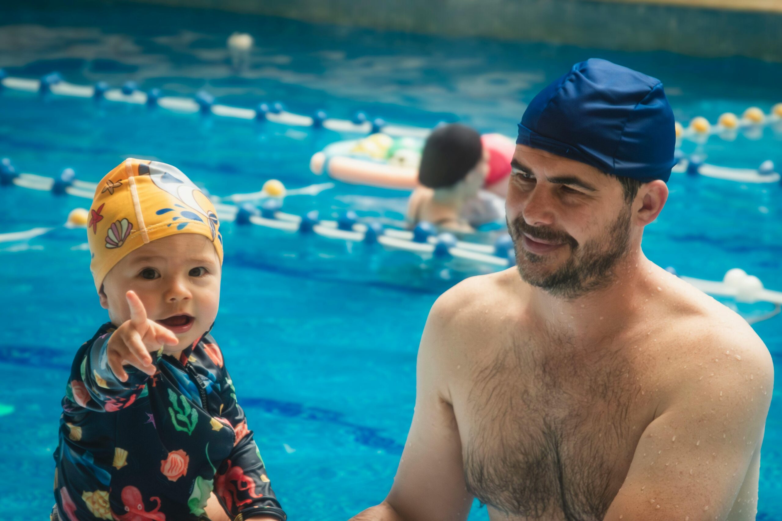 Father and child bond during a swimming lesson at an indoor pool.